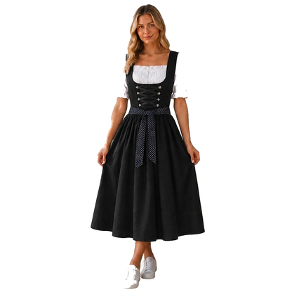 Model on a plain white background wears the black dirndl with white puff-sleeve blouse, polka-dot waist ribbon and white trainers, holding the skirt out. 1