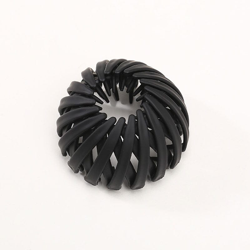 Single matte black spiral bird's-nest clip on a plain pale background, showing overlapping curved slats and inner prongs. 14