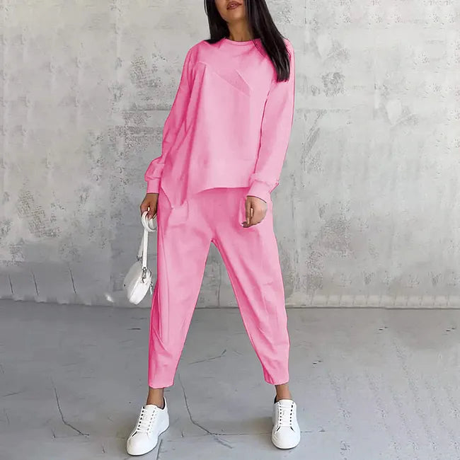 Model wearing the bright pink set, front view, with a small white bag and white trainers on a grey floor. 6