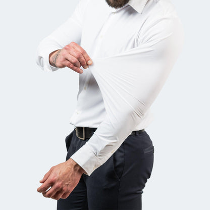 Model in a white shirt and dark trousers pulling the sleeve upwards from the forearm to demonstrate the stretchy fabric. 4