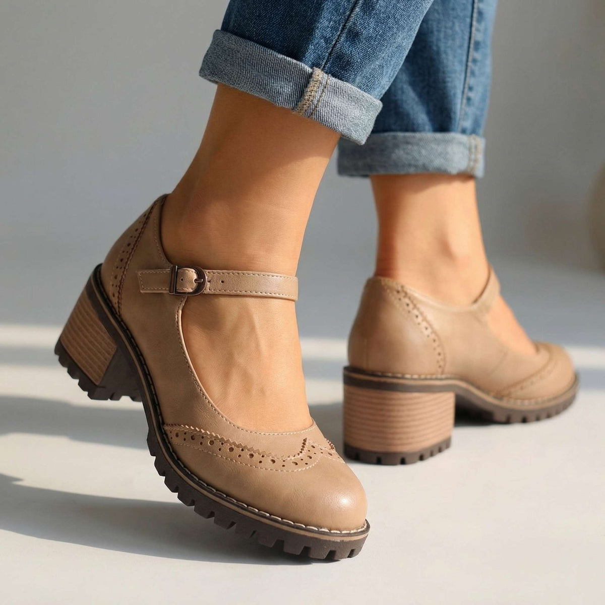 Beige brogue Mary Jane heels with perforated toe detail and stacked block heel, worn with cuffed jeans in a studio. 3