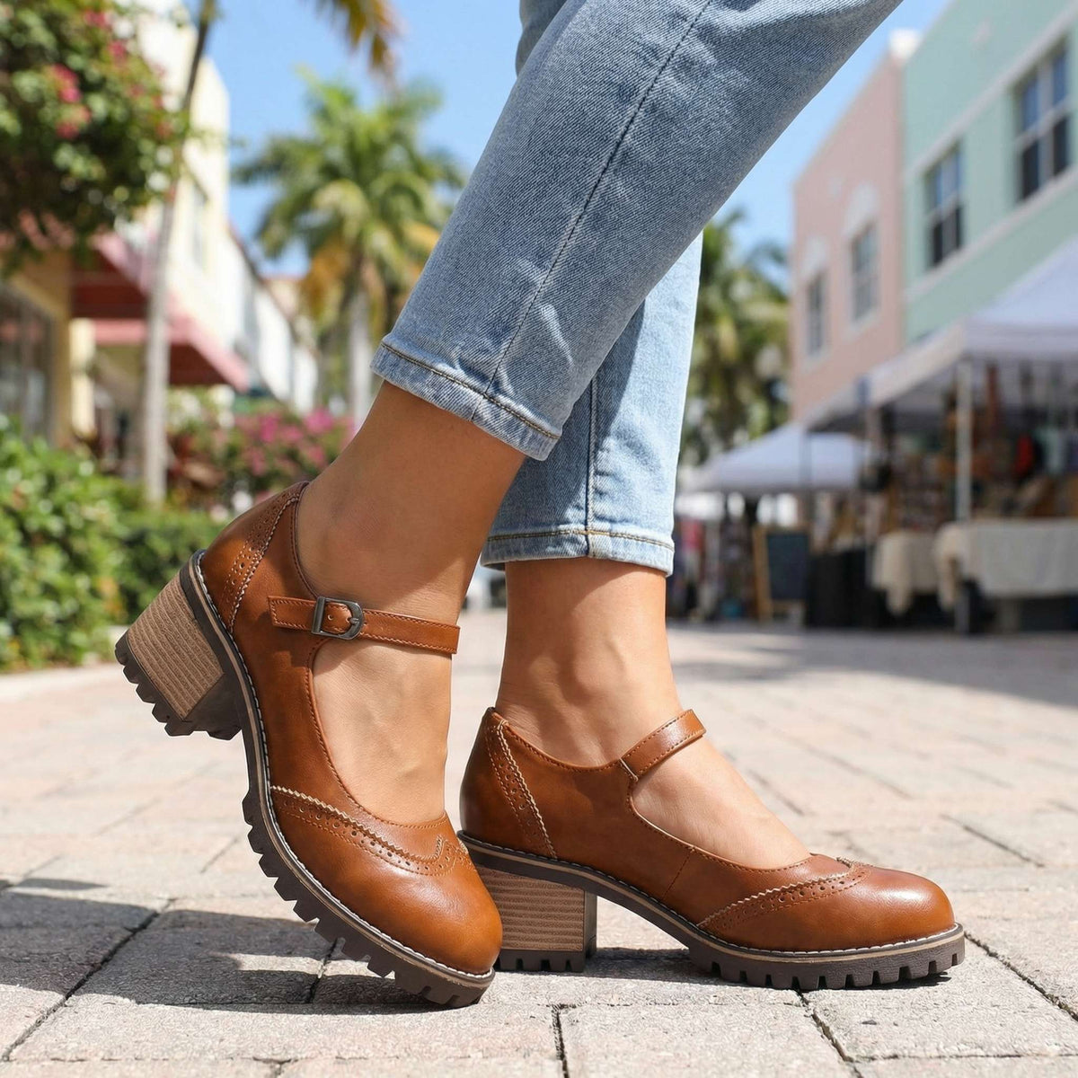 Tan brown Mary Jane heels with brogue toe stitching, worn with light jeans on a sunny pedestrian street. 5