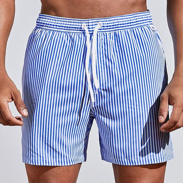 Model wearing royal blue and white vertically striped swim shorts with a white drawstring, shown from the front. 2