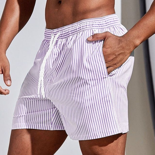 Model wearing lilac and white vertically striped swim shorts with a white drawstring, hand resting in the side pocket. 11