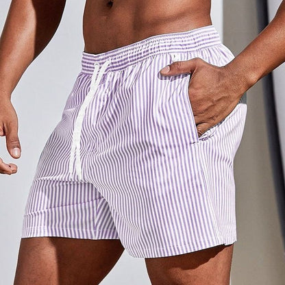 Model wearing lilac and white vertically striped swim shorts with a white drawstring, hand resting in the side pocket. 11