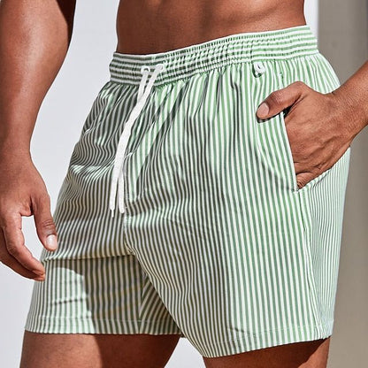 Model wearing light green and white vertically striped swim shorts with a white drawstring, one hand in the side pocket. 6