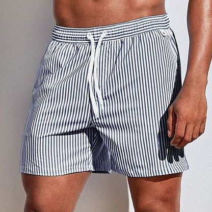 Model wearing navy and white vertically striped swim shorts with a white drawstring, shown from the front at thigh length. 13