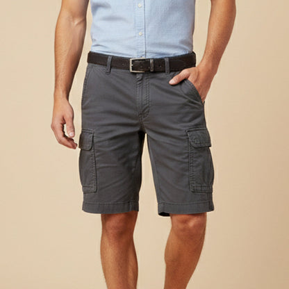 Man wearing dark grey cargo shorts with a light blue shirt and dark leather belt, one hand in his pocket. 12