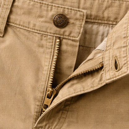 Close-up of the tan waistband, showing the metal button, brass zip partly open and the stitched fly. 6