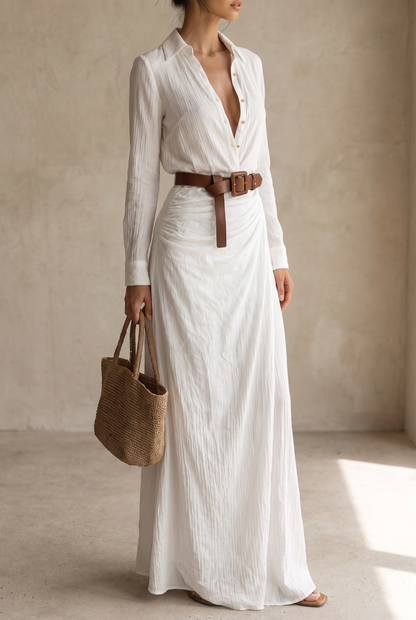 White version worn by a model holding a woven straw tote, three-quarter view with long sleeves, gold buttons and knotted brown belt. 9