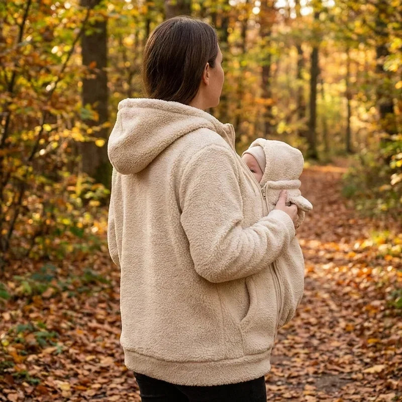 Rear view of a woman in the cream fleece hoodie with a baby in the front pouch on an autumn path. 12