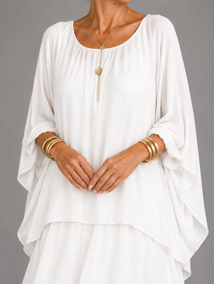 Upper body detail in white, showing the gathered round neckline, soft sleeves and a gold pendant necklace. 30