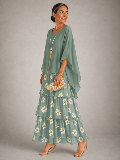 Side view of the dress with a plain sage green cape top over tiers printed with white daisies. 34