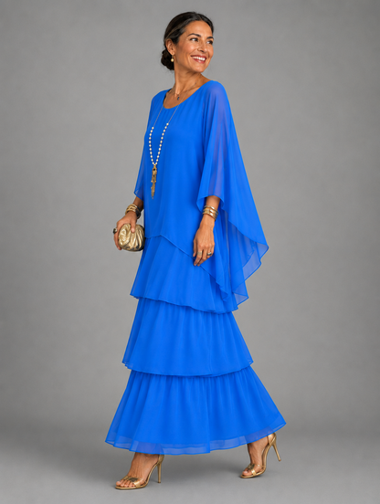 Side view of the tiered maxi dress in bright royal blue, worn with a gold clutch and heels. 25