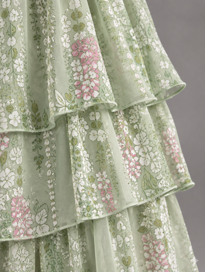 Close-up of sage green tiered ruffles printed with white and pink flowers, showing the fine edging on each layer. 47