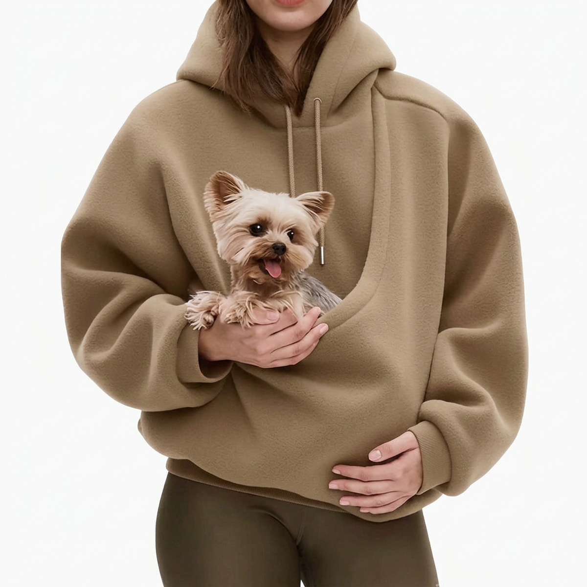 Woman in a tan fleece hoodie against a plain white background, holding a small terrier in the pouch. 4