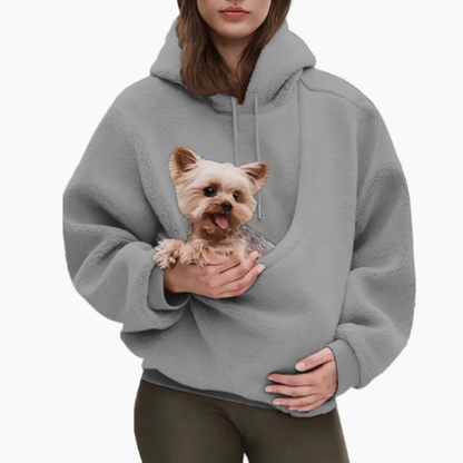 Woman in a grey teddy-fleece hoodie with olive leggings, holding a small terrier in the front pouch. 7