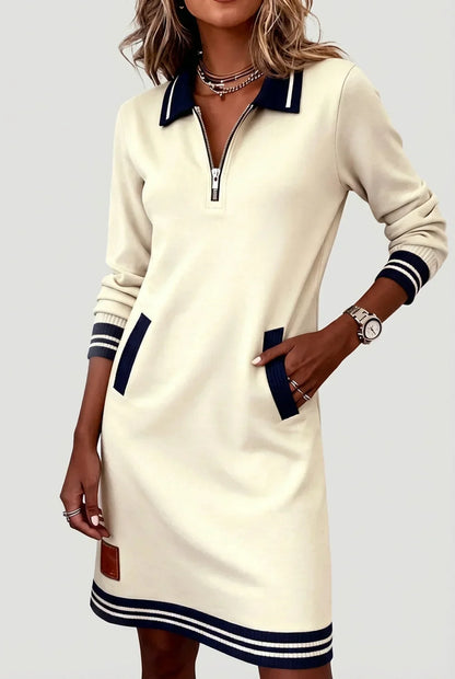 Model wearing the cream version with navy striped collar, cuffs and hem, one hand tucked into a pocket. 2