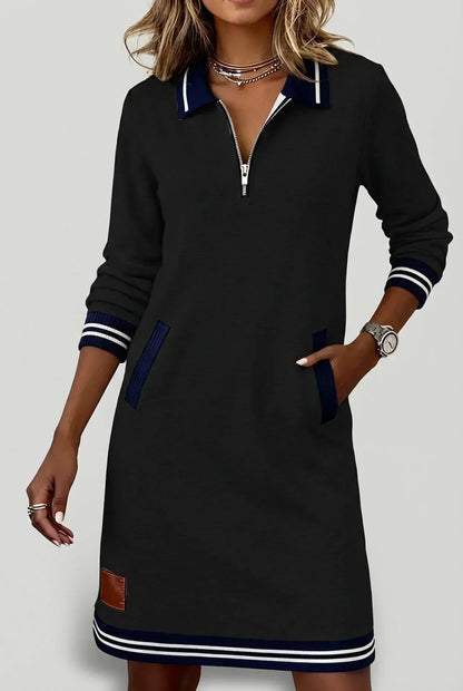 Model in the black dress with hand in pocket, showing navy ribbed pocket trim, zip neckline and striped hem. 11