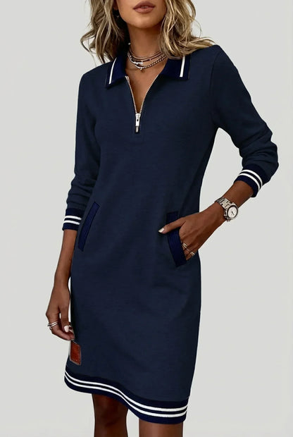Model in the navy blue dress, hand in a pocket, showing the half-zip collar, striped cuffs and leather-look patch. 3