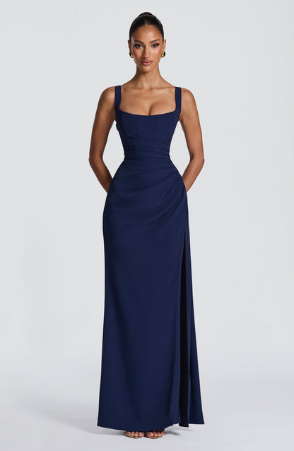Front view of the navy maxi dress with hands behind the back, showing corset-seamed bodice and side slit. 13