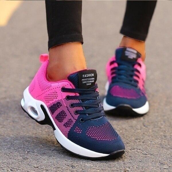 Worn outdoors with black leggings, a mesh trainer in pink fading to navy blue, with navy laces and a white air-cushion sole. 2