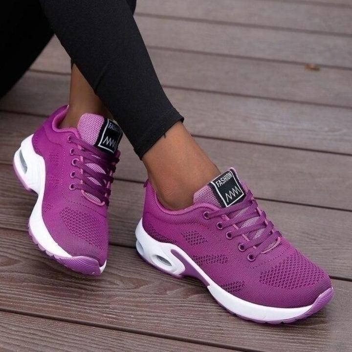 Purple mesh trainers with white air-cushion midsoles and lilac heel tabs, worn with black leggings on a wooden deck. 4