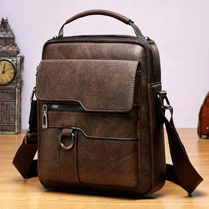 Dark brown version of the shoulder bag with front flap, zip pocket and metal ring, on a wooden surface. 4