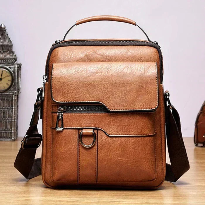 Front view of the tan shoulder bag showing the flap pocket, zip pocket, metal ring and adjustable brown strap. 5