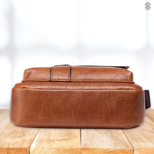 Underside of the tan shoulder bag, showing the flat base and stitched seams, resting on a wooden surface. 11