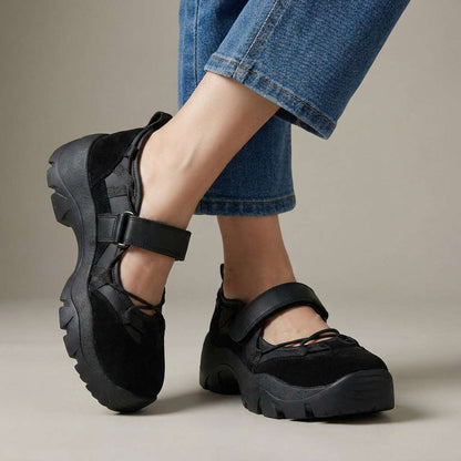 All-black suede and leather shoes with a hook-and-loop strap and chunky black soles, worn with cropped blue jeans. 5