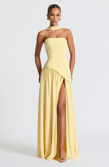 Front view of the pale yellow strapless dress on a model, with a fitted bodice, asymmetric waist seam and high skirt slit. 3