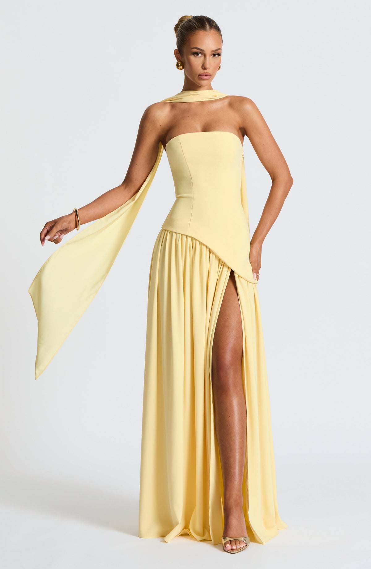 Model in the pale yellow strapless dress with a long scarf trailing from one arm, showing the gathered skirt and thigh-high slit. 2