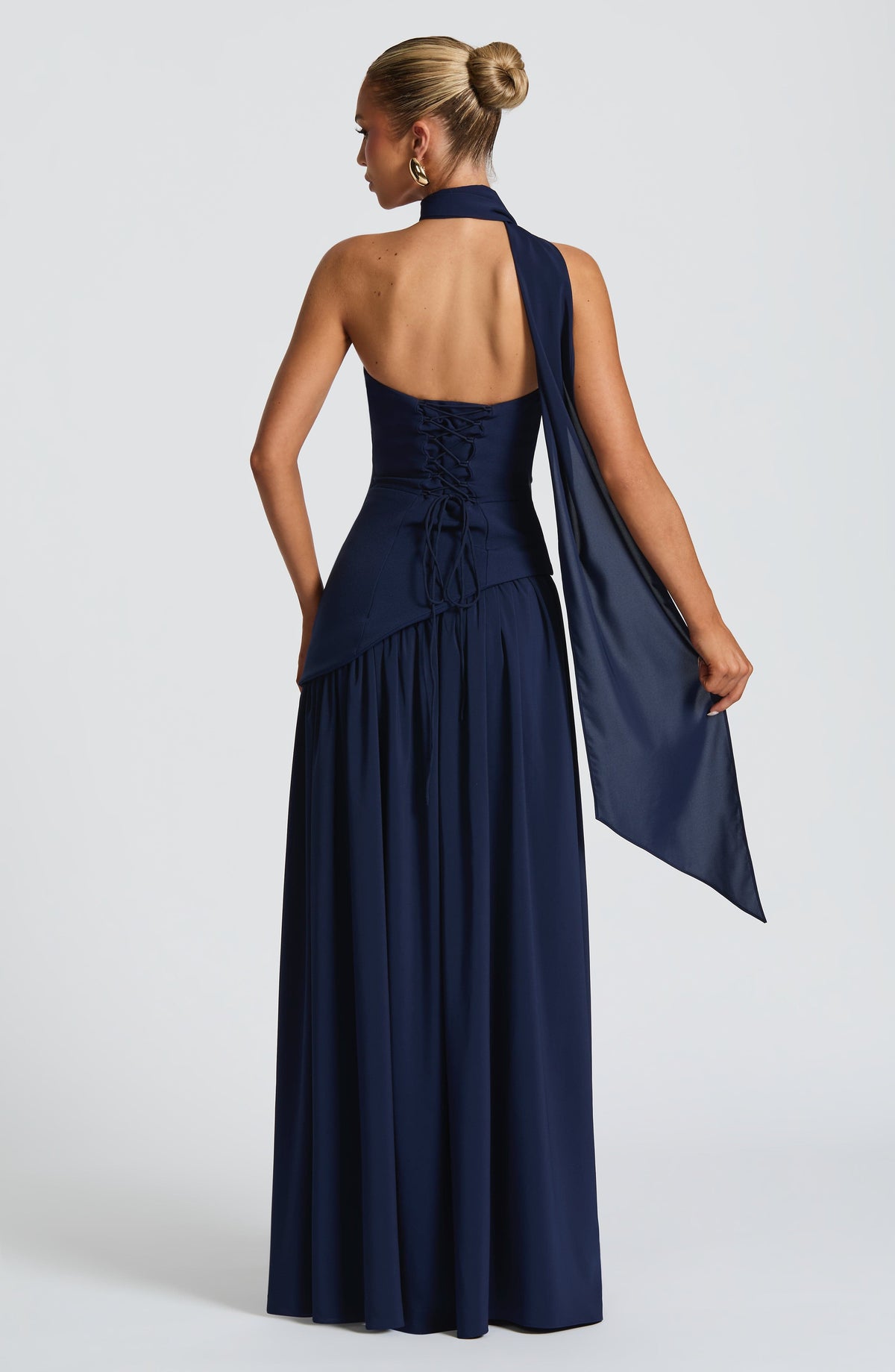 Back view of the navy blue dress, showing the lace-up corset back and a scarf draped over one shoulder and arm. 8
