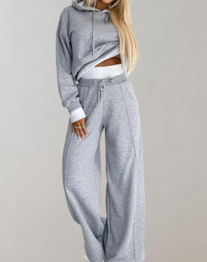 Model in the grey marl set with drawstring waist and centre front seam on the wide trousers, one hand on hip. 3