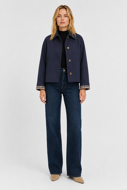 Full-length front view of the navy jacket buttoned over a black top, with dark wide-leg jeans and beige boots. 18