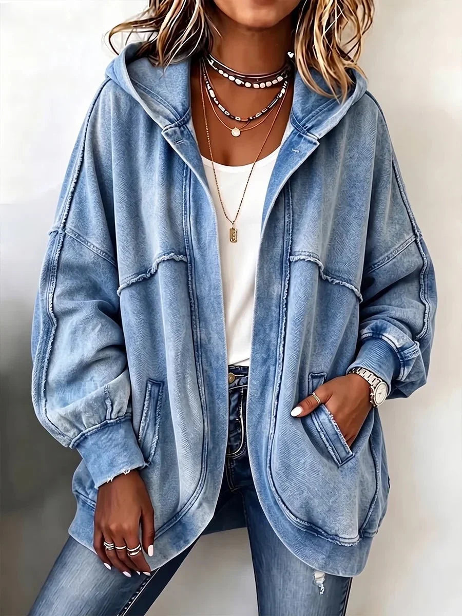 Close front view of a model wearing the open blue washed hooded jacket over a white top, one hand in a pocket. 1