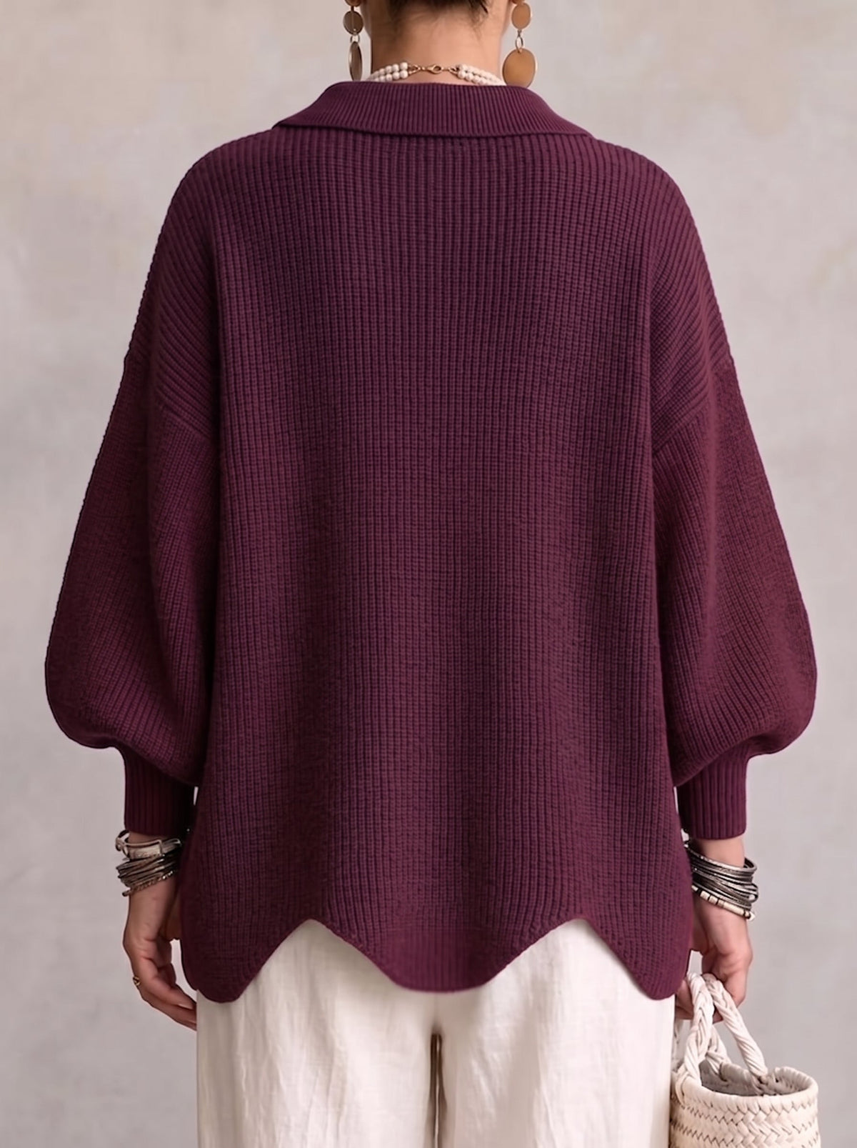 Back view of the plum purple cardigan on a model, showing the ribbed knit, folded collar and wavy hem. 4