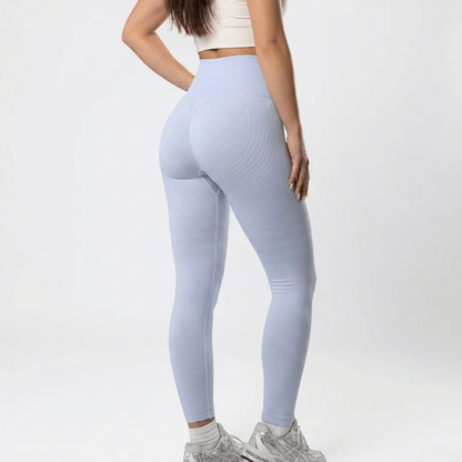 Back view of pale lilac high-waisted leggings with subtle texture, worn with a cream crop top and grey trainers. 24