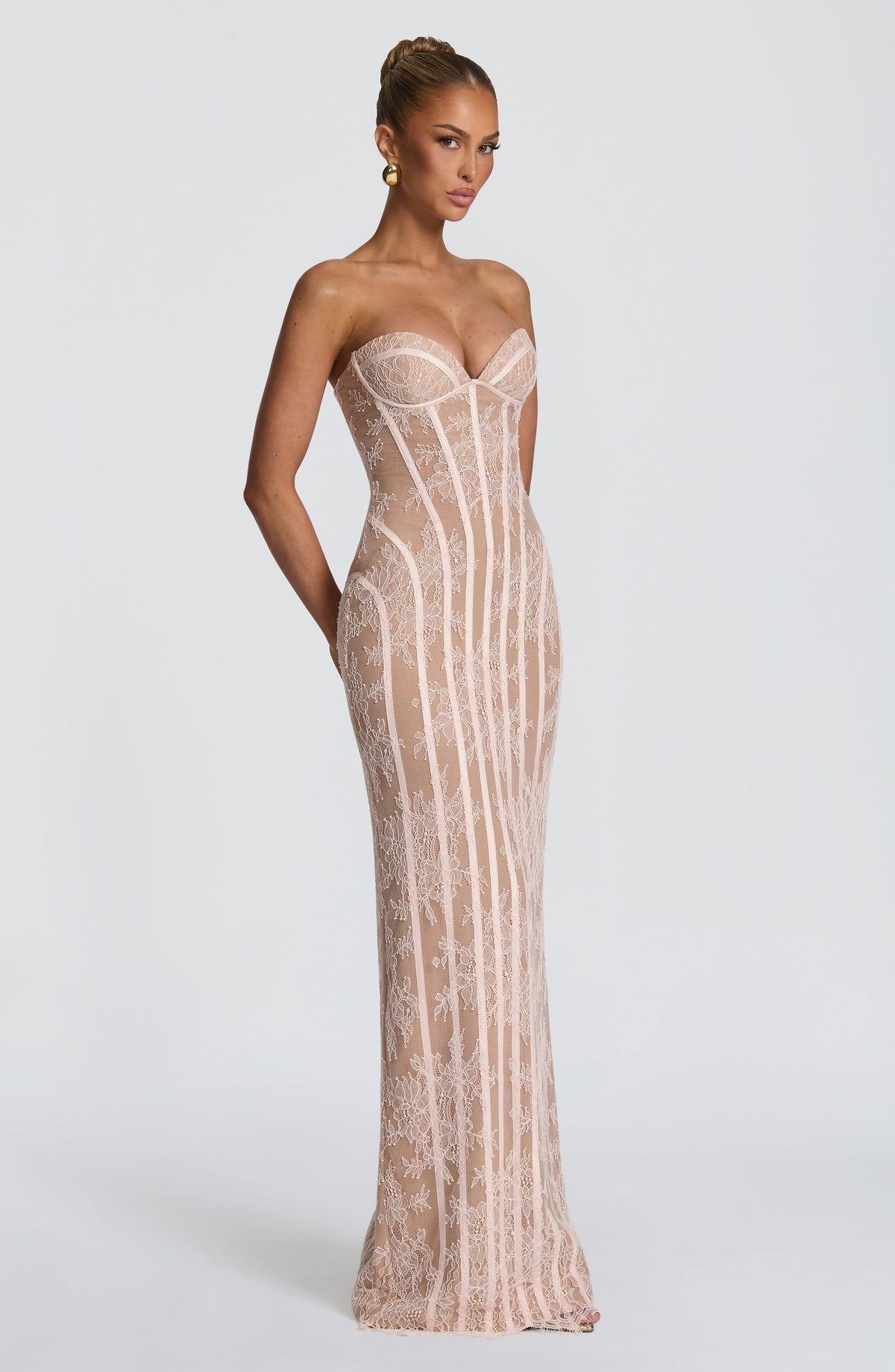 Angled view of the blush pink lace dress, showing the sweetheart neckline, curved seams at the waist and hip, and the long fitted skirt. 16