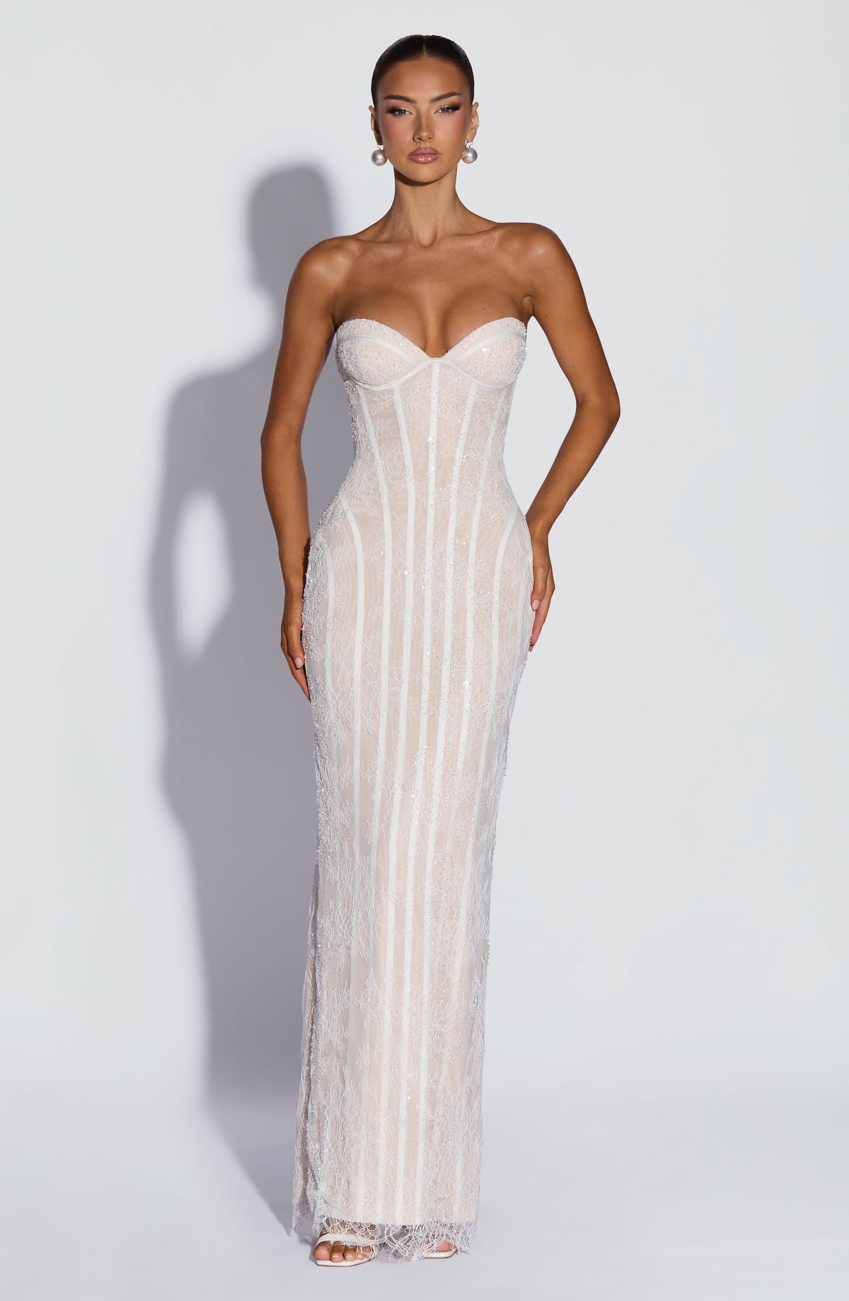 Front view of the white lace version with subtle beading, worn with pearl earrings and white heeled sandals against a pale background. 9