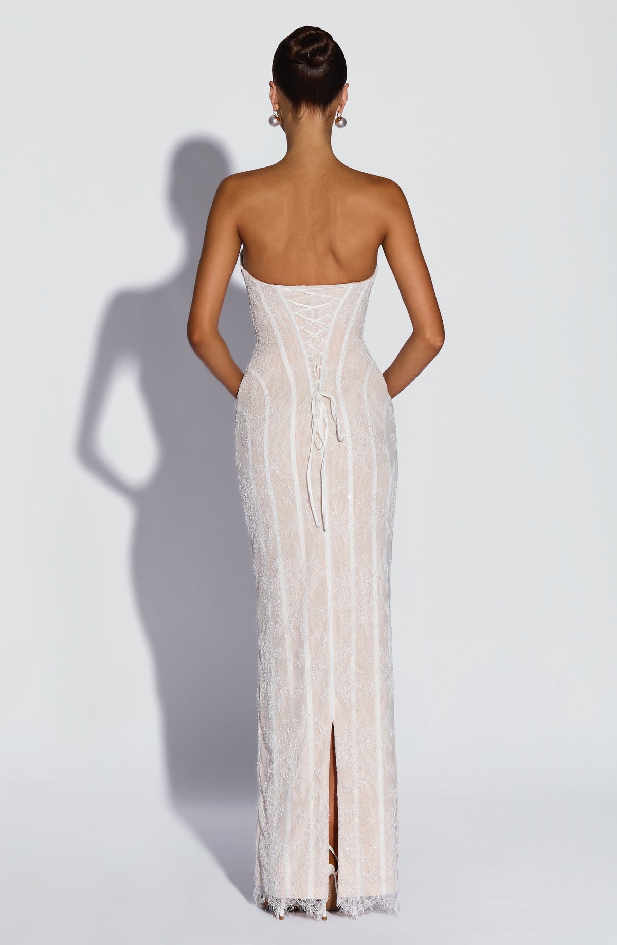 Back view of the white beaded lace dress, showing the lace-up corset back with long ties and a centre slit. 10