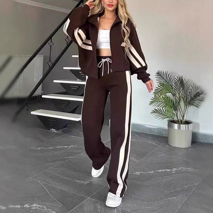 Model walking in the dark brown set with cream side stripes and drawstring waist, beside a staircase and potted plant. 8