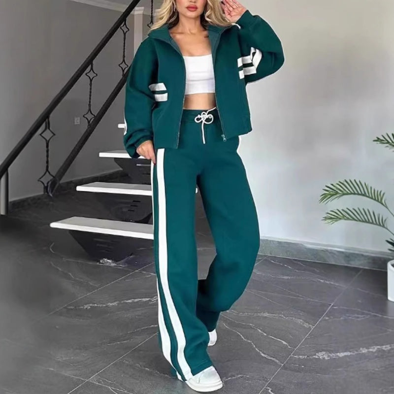 Model wearing the dark green set with white side stripes and a white drawstring, standing beside a staircase. 5