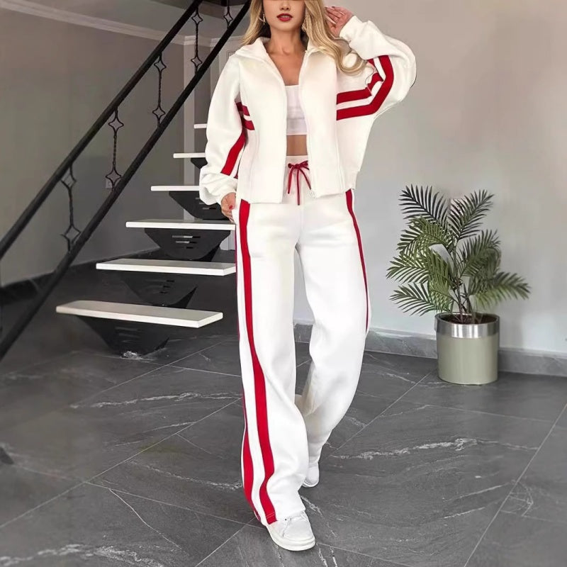 Model wearing the white set with red stripes, jacket zipped open over a white crop top, standing by a staircase. 1