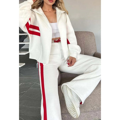 Close-up of the white and red set worn seated on an armchair, showing the zip front and red drawstring waist. 2