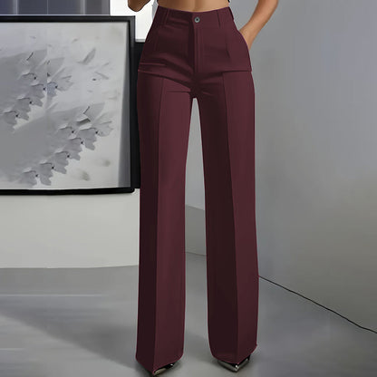 Front view of burgundy high-waisted straight-leg trousers with a sharp centre crease, worn by a model in a grey room. 4
