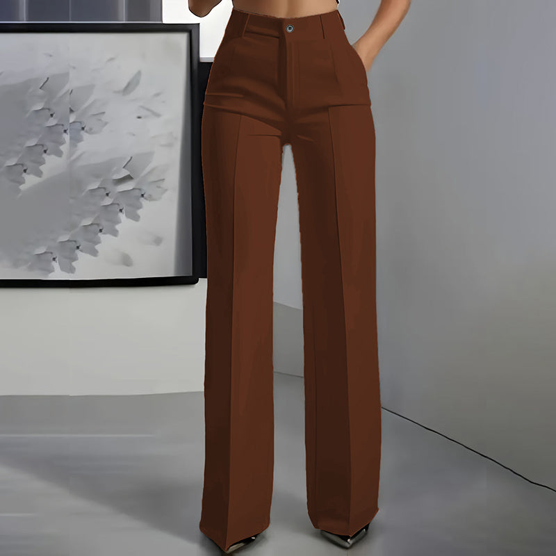 Front view of brown high-waisted straight-leg trousers with pressed centre crease, worn by a model in a grey room. 8