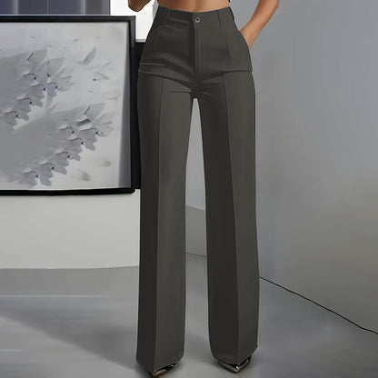 Front view of dark grey high-waisted straight-leg trousers with centre crease and button waist, worn by a model in a grey room. 6