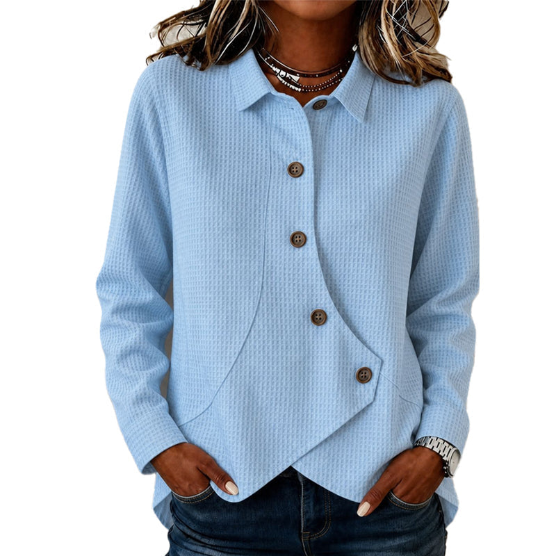Model wearing the waffle-knit top in pale light blue, hands in jeans pockets, showing the collar, brown buttons and curved asymmetric hem. 3